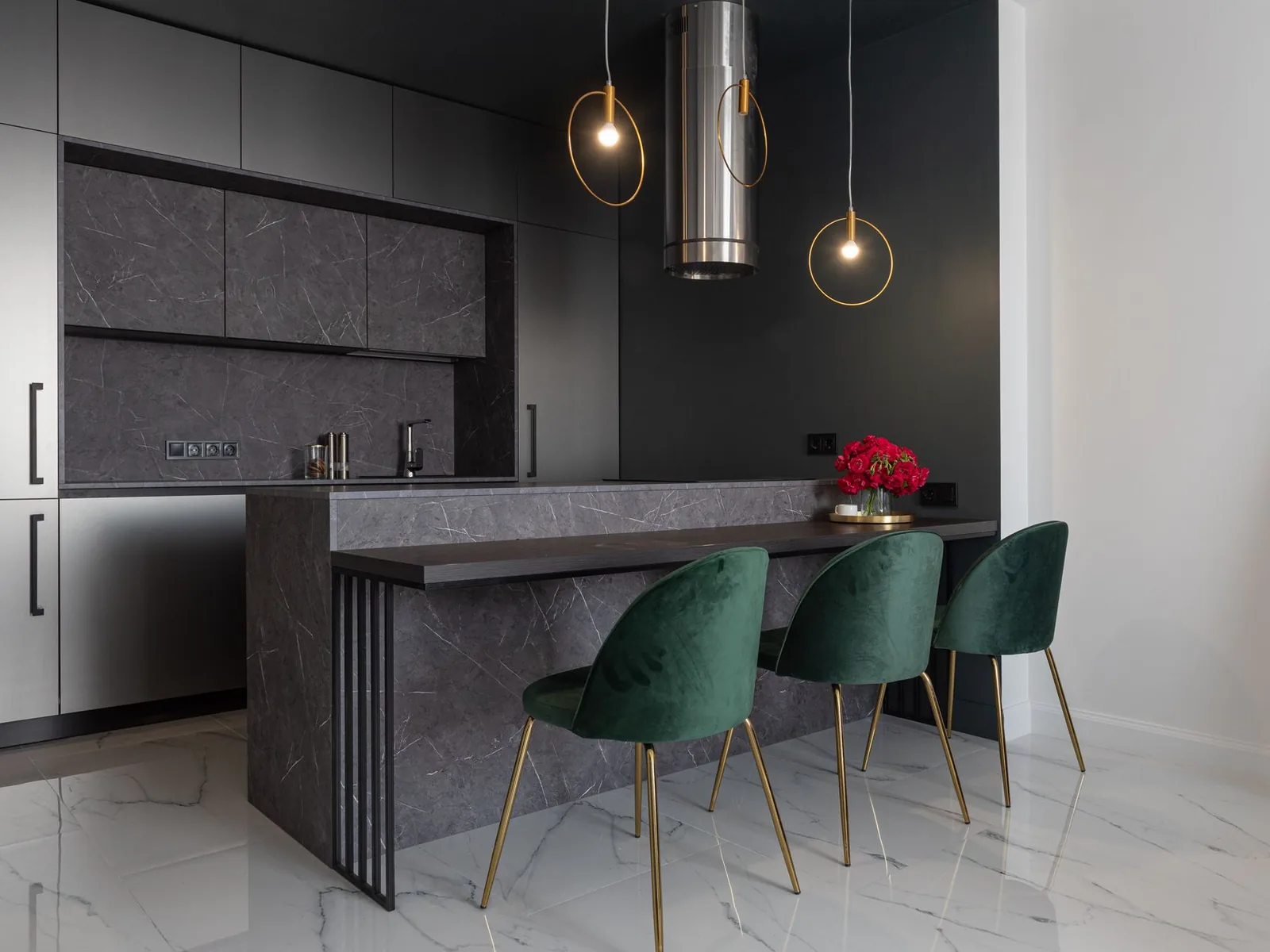 Bespoke fitted kitchen with dark cabinetry, a stone island and brass pendant lighting