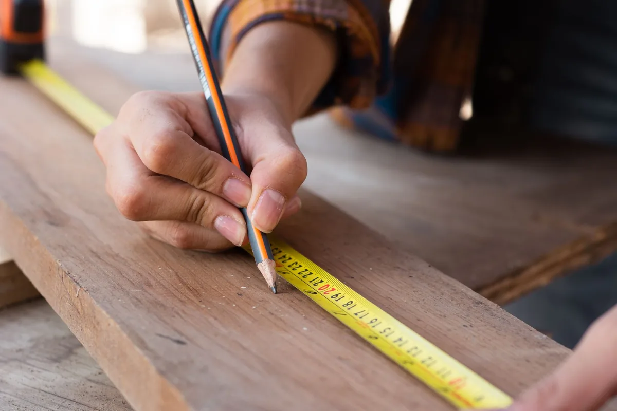 Marking out a length of timber with a pencil and tape measure